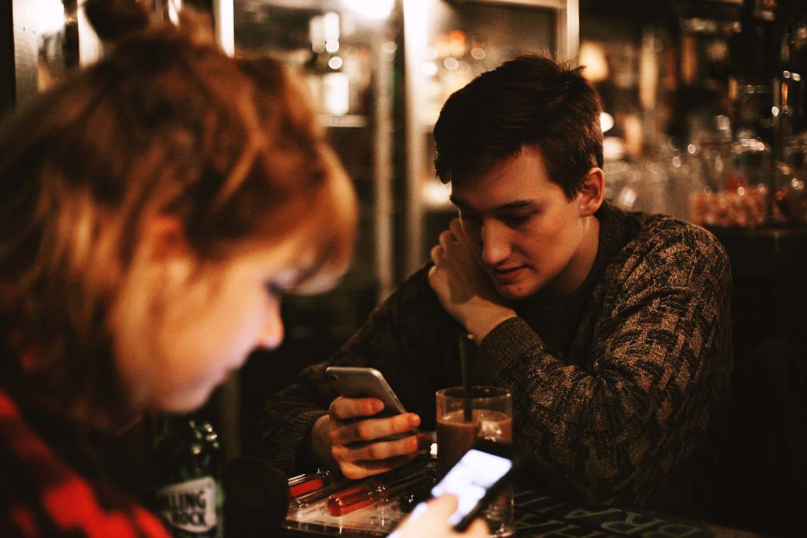 Frau und Mann mit Smartphone in einer Bar