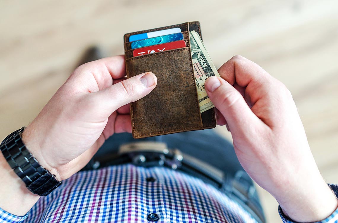 Mann steckt Geldschein in seine Geldbörse.