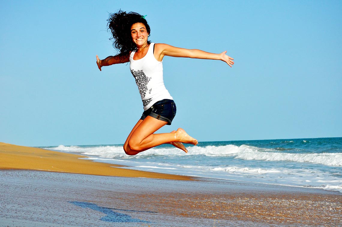 Frau springt am Strand in die Luft